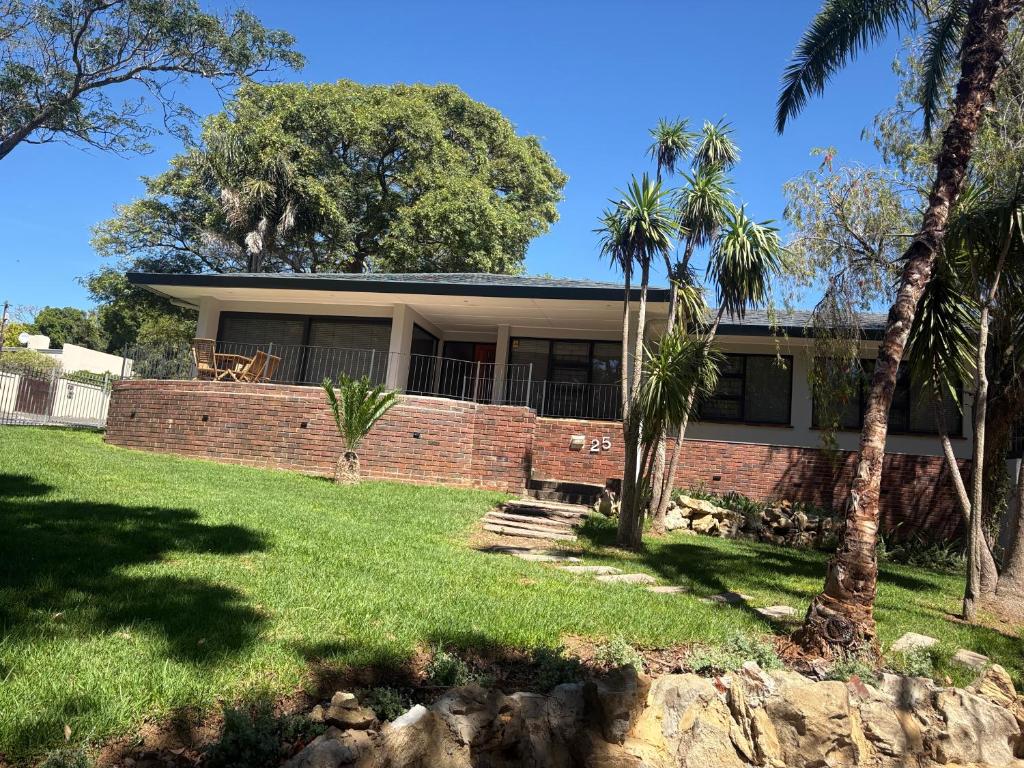 a house with a brick wall and palm trees at Prime location in Welgemoed in Welgemoed
