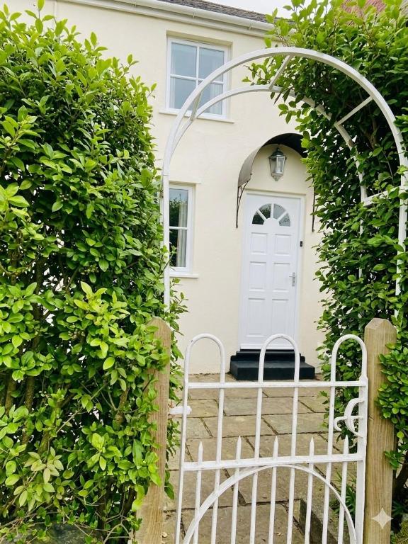 a white gate in front of a house at Coach House Hideaway in Warminster