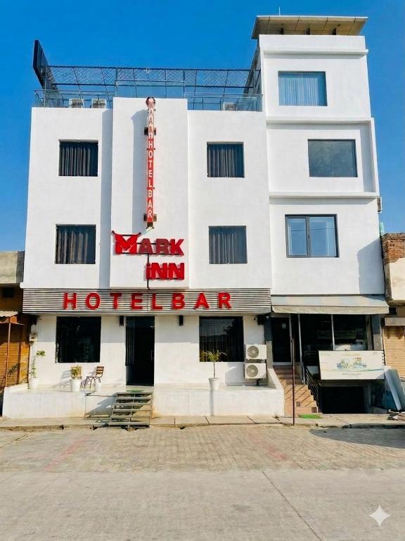 a white building with a red sign on it at Mark inn hotel in Hanumāngarh