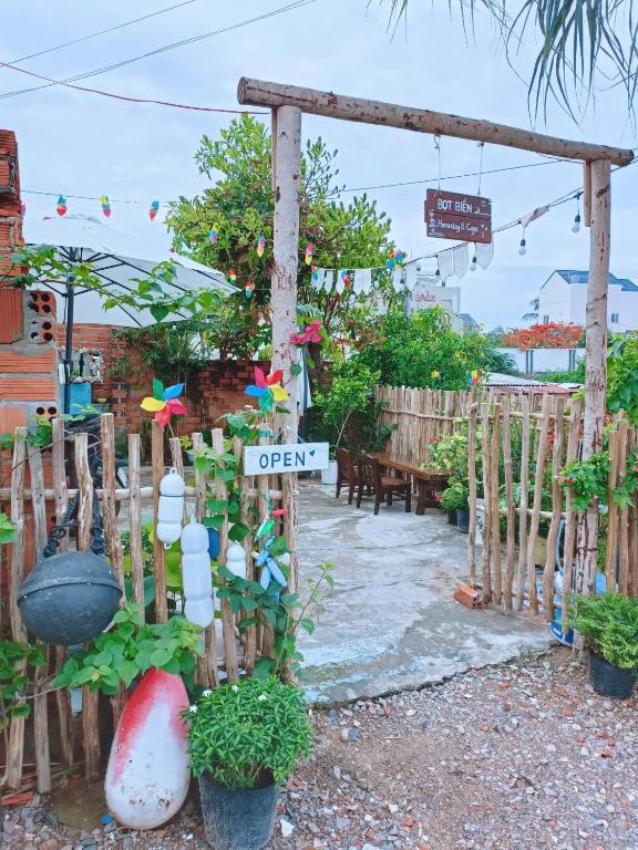a garden with a sign that says open at Bot Bien Homestay in Mui Ne