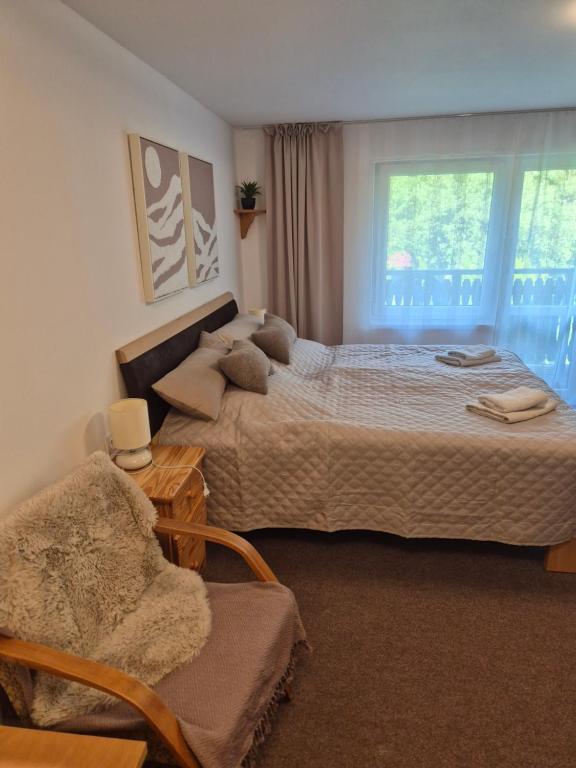a bedroom with two beds and a chair and a window at Nevesta hôľ pod Chopkom in Bystrá