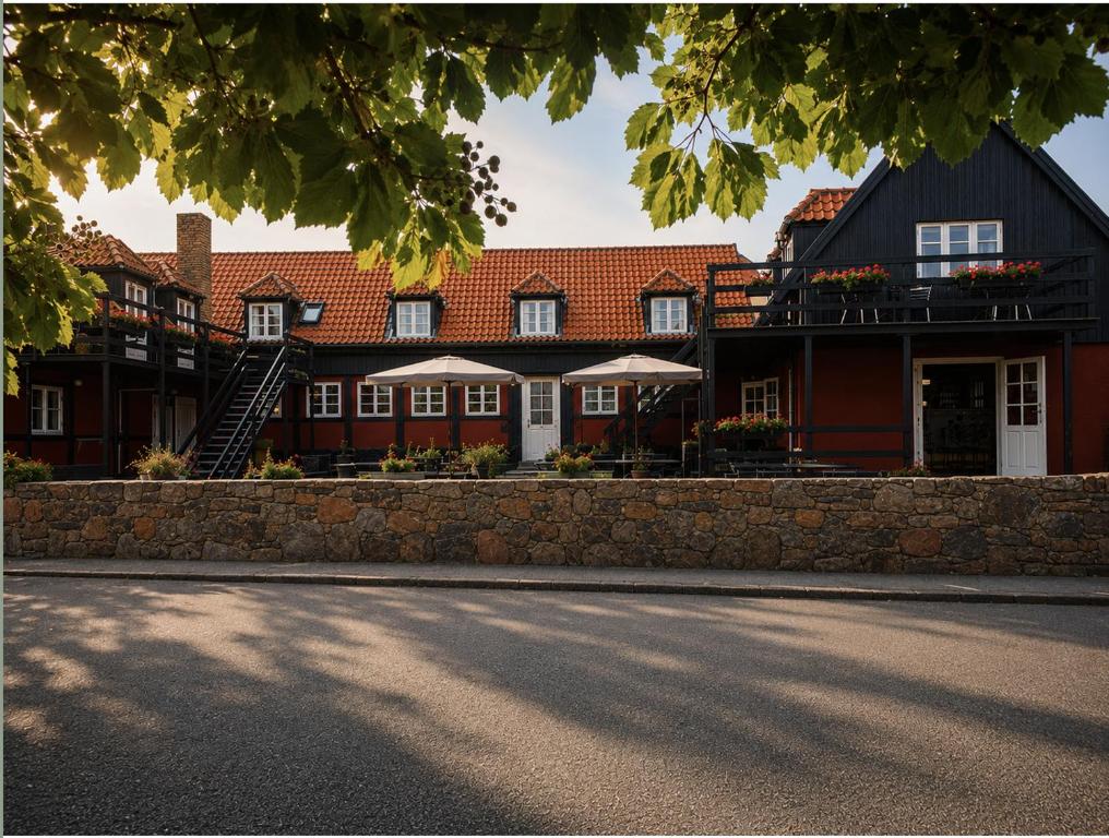 a large red building with white windows and a street at Klippen Hotel - Skt Jørgens Gaard in Gudhjem