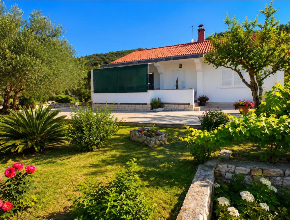 a house with a green screen in the yard at Holiday house Solis in Rab