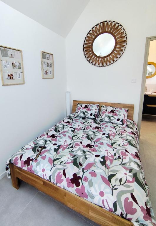 a bedroom with a bed with a floral comforter and a mirror at La maison du hérisson in Flines-lès-Mortagne