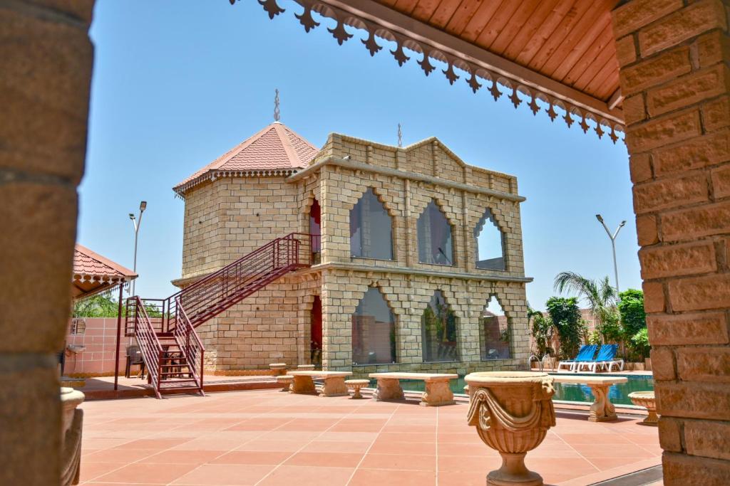 a large brick building with a staircase in a courtyard at The Royal Valley Resort in Chotila