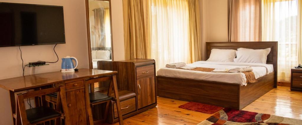 a bedroom with a bed with a dresser and a television at GaYuel in Thimphu
