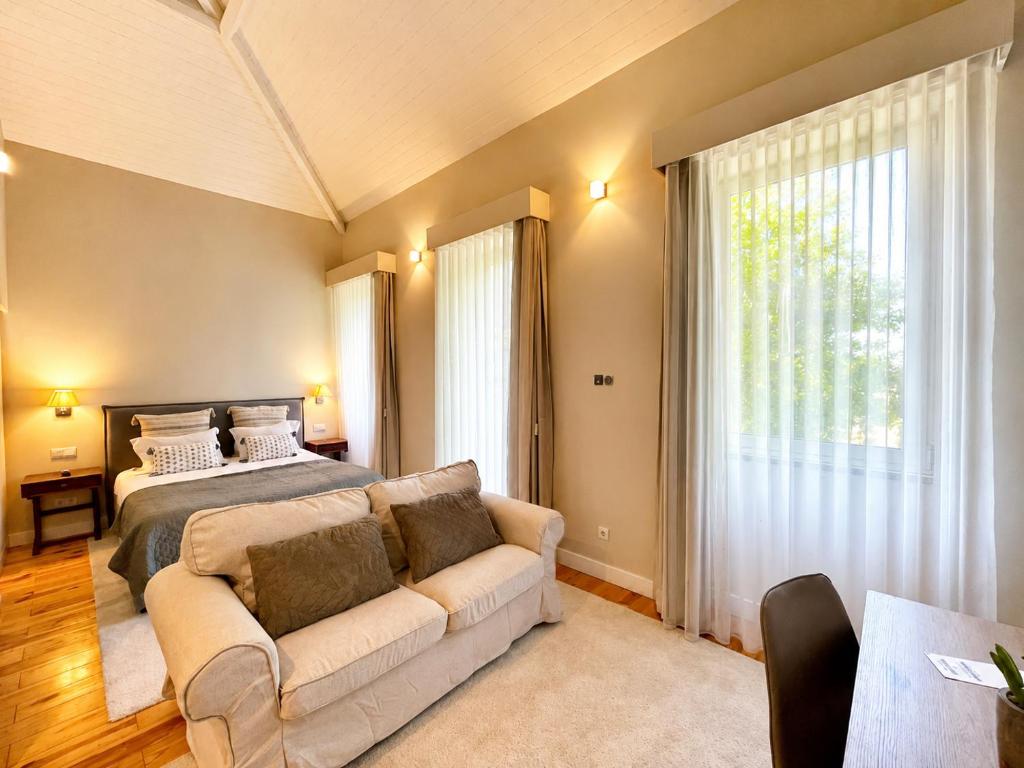 a bedroom with a bed and a couch in front of a window at BlueCap by MyTrip Porto in Matosinhos