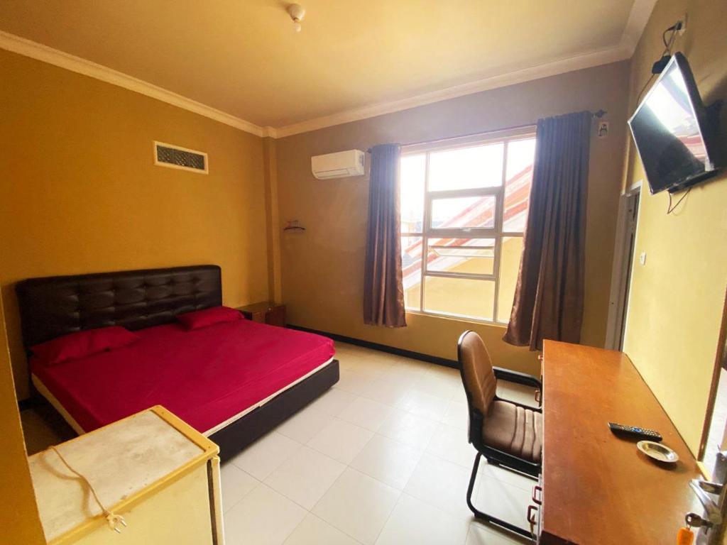 a bedroom with a red bed and a window at Rian Kost - Hotel Penginapan Murah Pusat Kota Palembang in Palembang