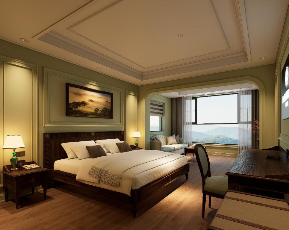 a bedroom with a bed and a desk and a window at Dalabiang Hotel in Da Lat