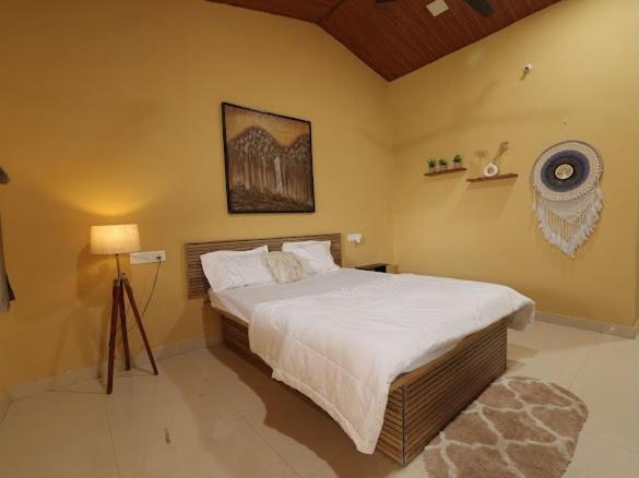 a bedroom with a large bed and a lamp at Veranda hillside retreat in Kharakvasla