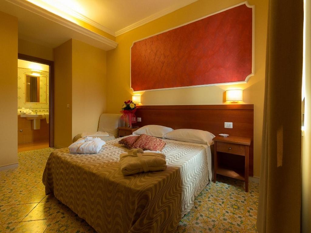 Una habitación de hotel con una cama y una mesa con toallas. en Fortuna Village Pompei en Pompei