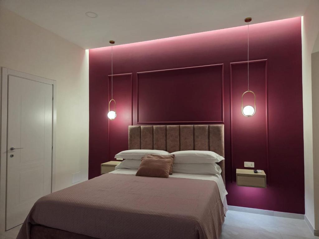a bedroom with a large bed with purple walls at Suite in centro in Aversa