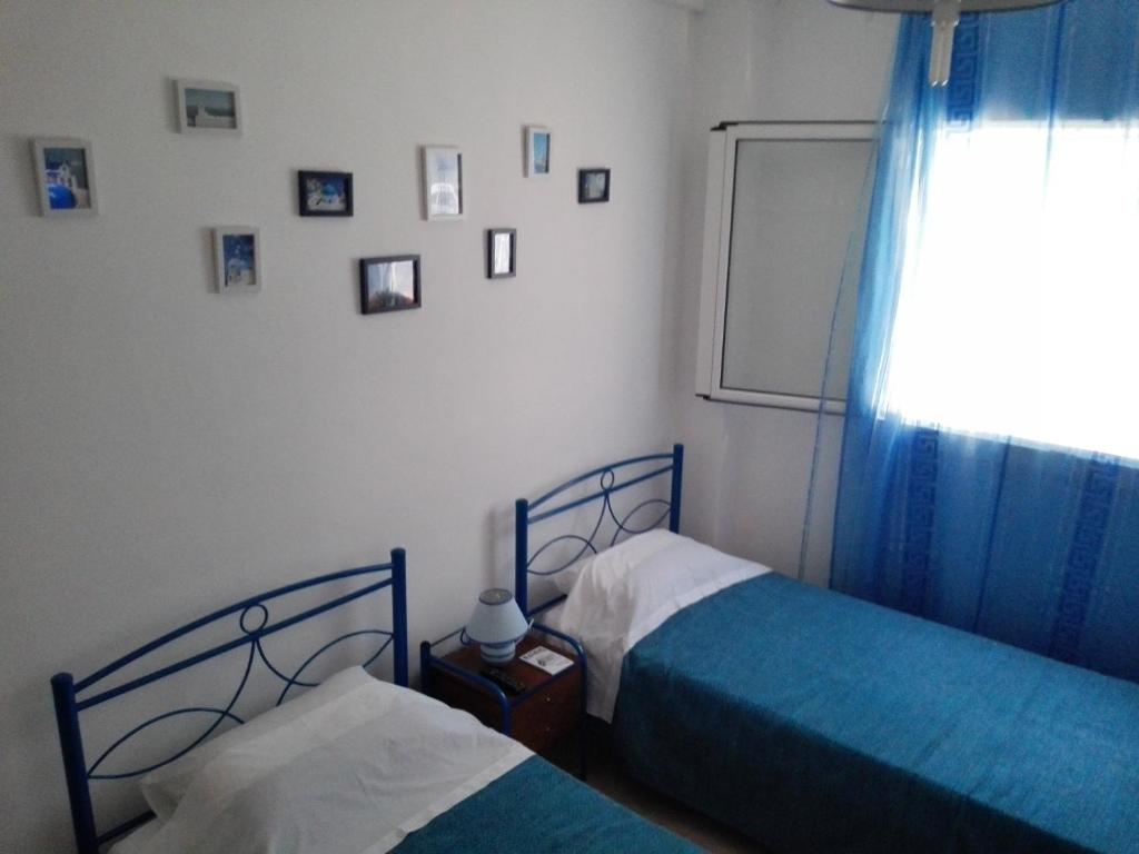 um quarto com 2 camas e uma janela com fotografias na parede em Cosy Apartment Pinotsi em Atenas