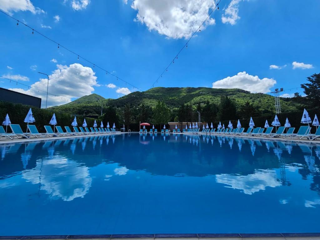 a swimming pool with blue water and white chairs at Serenata Korcare Resort in Tirana