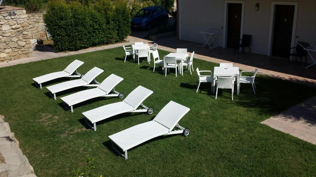 a group of white chairs and tables on the grass at Kasale B&B Country House in Torretta