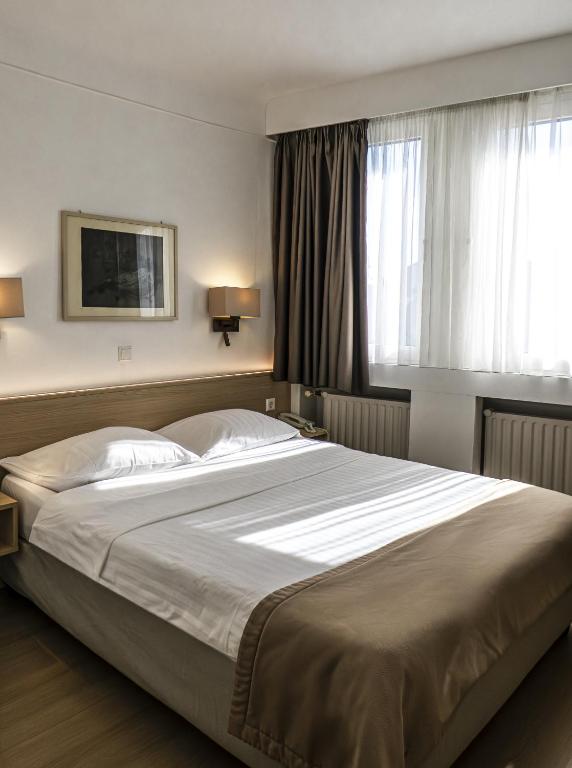 ein Schlafzimmer mit einem großen Bett und einem großen Fenster in der Unterkunft Hotel Francais in Luxemburg (Stadt)