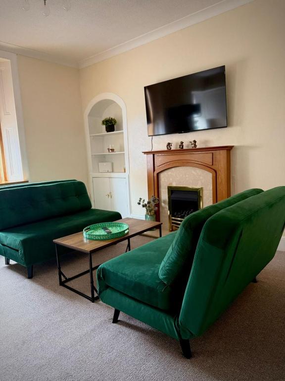 a living room with two green couches and a fireplace at Coorie in Inverness