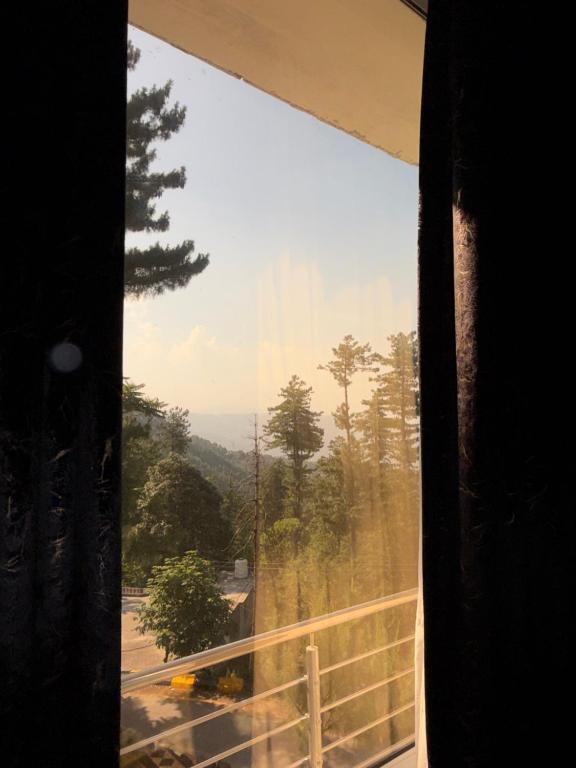a window with a view of a road and trees at Nizalia resorts in Patriata