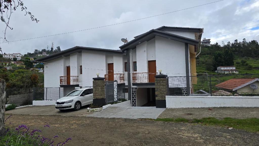 a white house with a car parked in front of it at Vedhas Holidays in Kodaikānāl