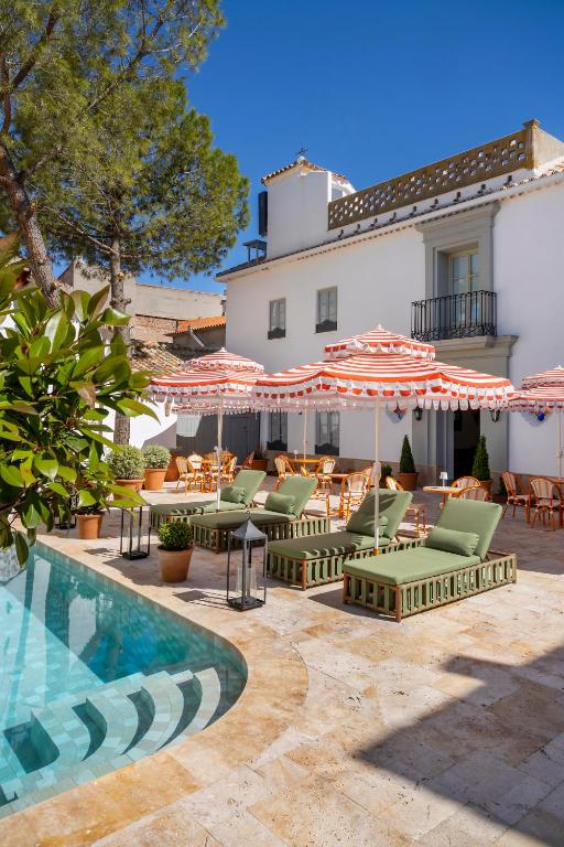 a patio with chairs and umbrellas next to a pool at Hotel Boutique Casa Treviño in Campo de Criptana