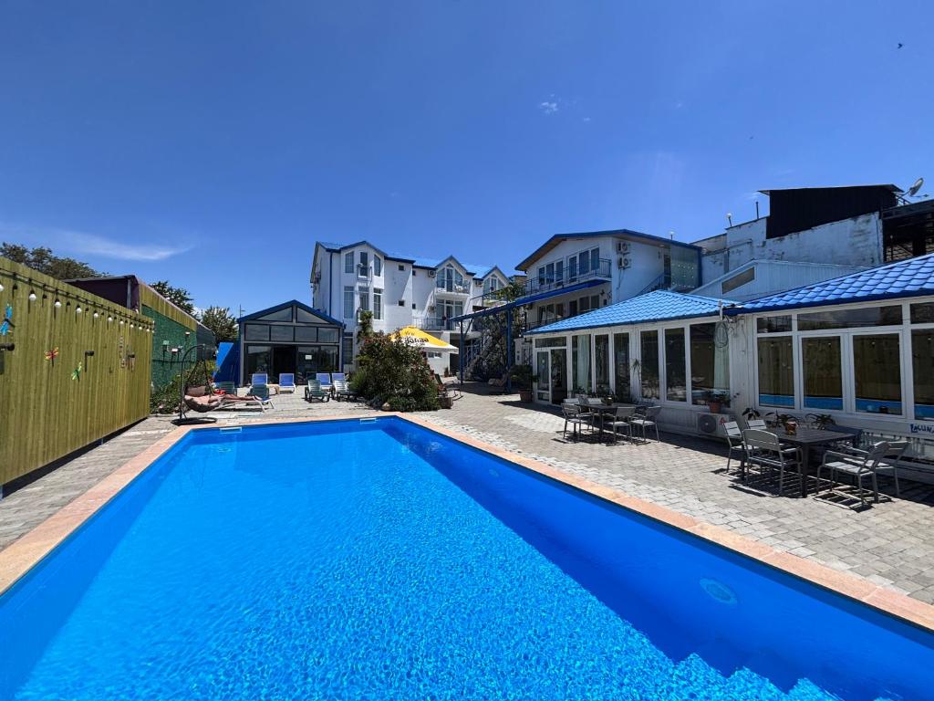 a large blue swimming pool next to a building at Laguna Boutique Hotel Bazaleti Lake in Dushetʼi
