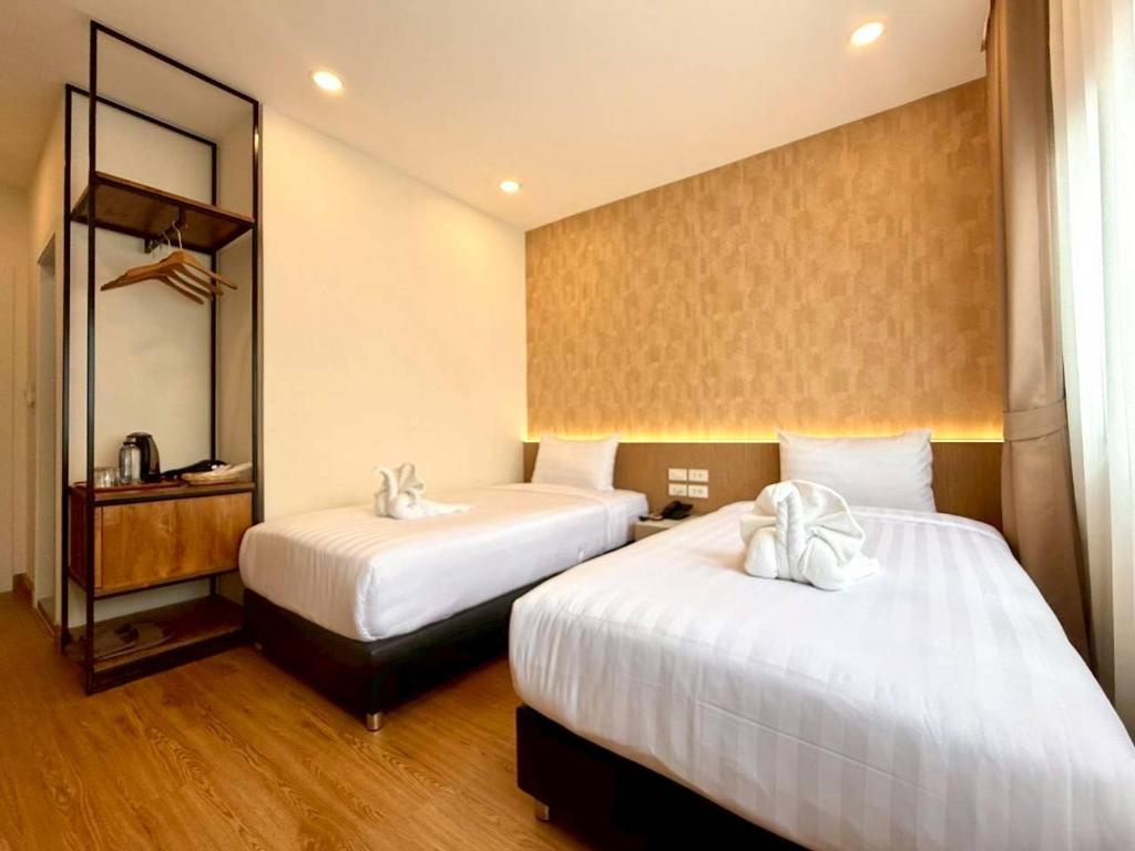 ein Hotelzimmer mit zwei Betten und einem Spiegel in der Unterkunft Believeinn in Bangkok