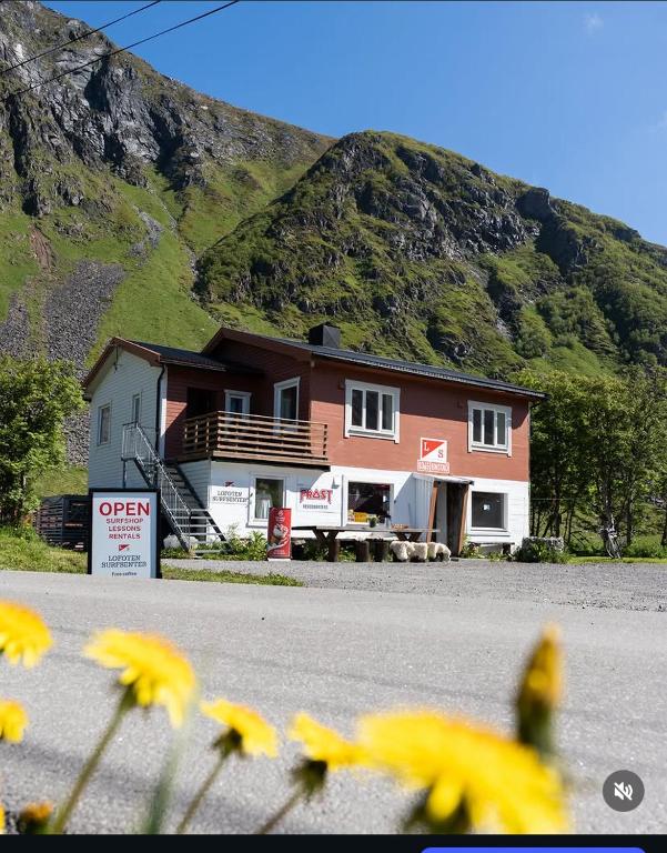 a house on the side of a road with a mountain at Unstad Surfpacker Hostel in Unnstad