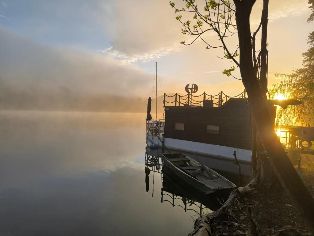 a boat is docked on a lake in the sunrise at Hausbót Slapy in Dublovice