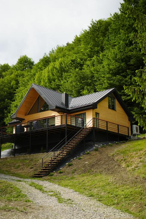 a yellow house with a black roof on a hill at Три сосни in Kosiv