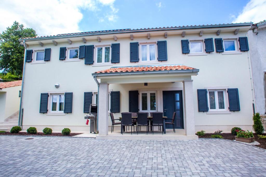 a white house with black chairs and a patio at Villa Orljak in Lanišće