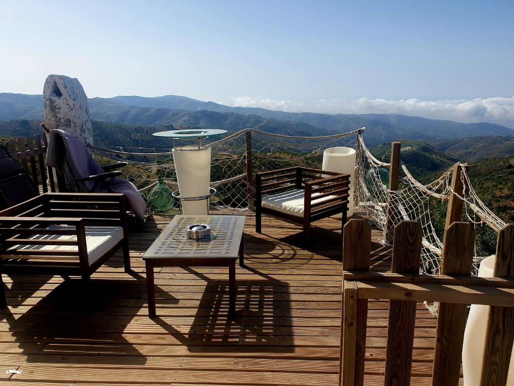 a wooden deck with chairs and a table with a view at Cortijo Saucillo in Albondón