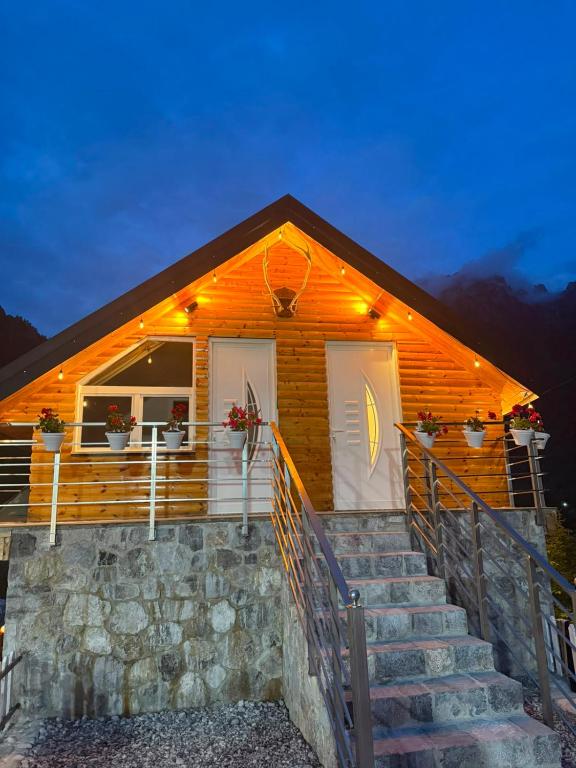 a log cabin with stairs leading to two doors at Guesthouse Kurora e Maleve in Ndërlysaj
