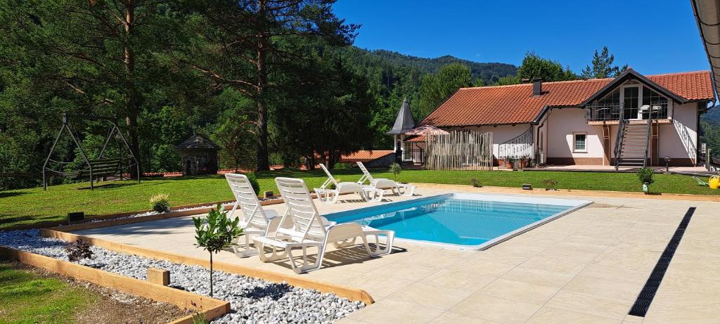 a swimming pool with white chairs and a house at Apartments Reida in Most na Soči