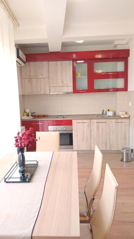 a kitchen with a table with chairs and red cabinets at WING 3 apartman ,,BC ,, in Jagodina