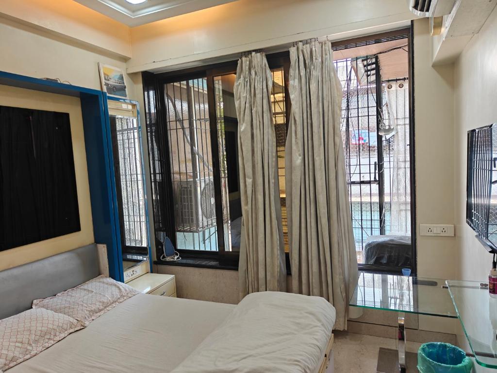 a bedroom with a bed and a window at Meenaji's home in Mumbai