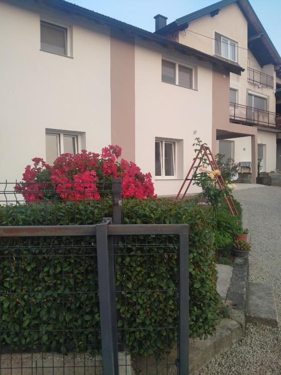 a white house with red flowers in front of it at Apartman Ema in Bihać