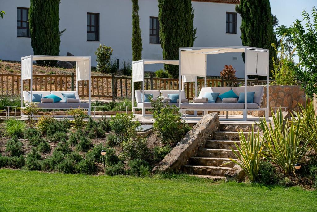 a garden with two white couches in a yard at Hospes Palacio de Arenales & Spa in Cáceres