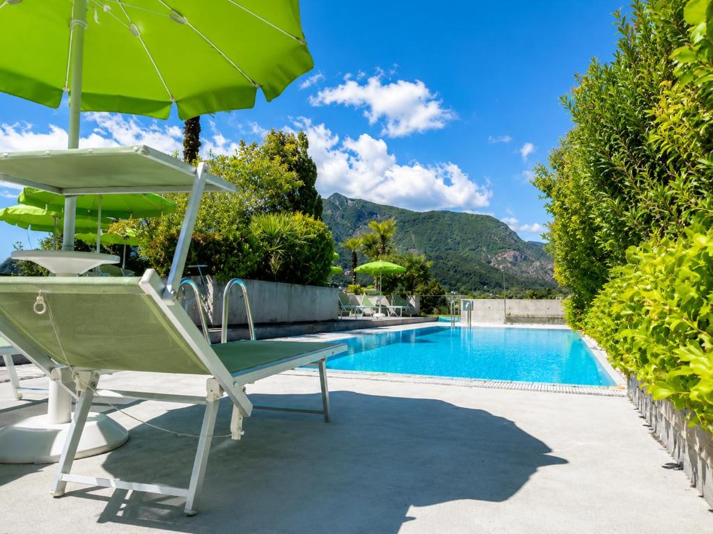 a chair with an umbrella next to a swimming pool at Hotel Nessi Locarno in Locarno