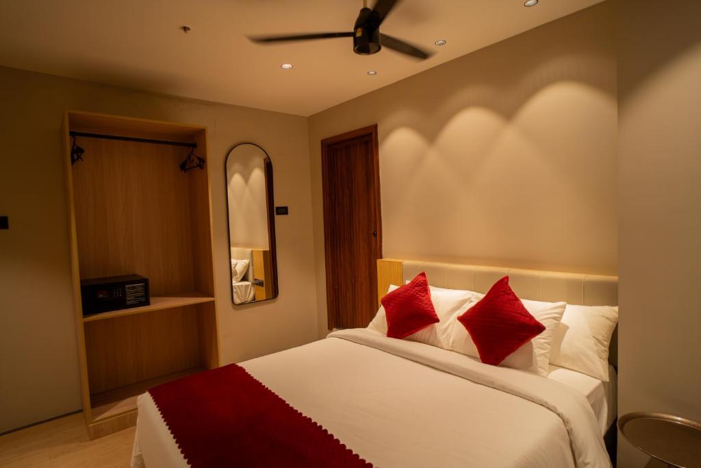 a bedroom with a bed with red pillows at Hotel Vdara Bliss in Vijayawāda