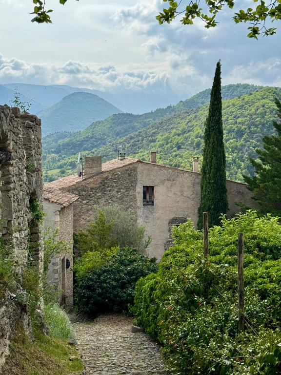 an old stone building with mountains in the background at Portail Sainte Marie in Montbrun-les-Bains