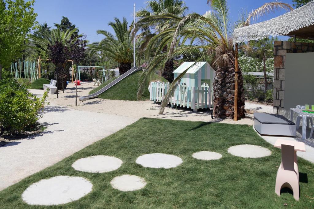 a park with a playground with palm trees and a slide at Ekies All Senses Resort, a Member of Design Hotels in Vourvourou