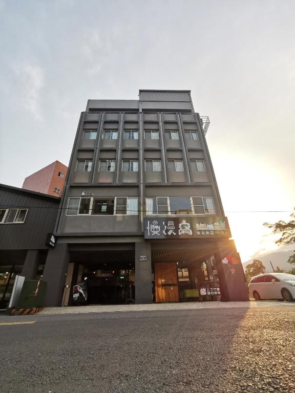 a tall building with a car parked in front of it at Slow Wow Hot Spring Hotel in Jiaoxi