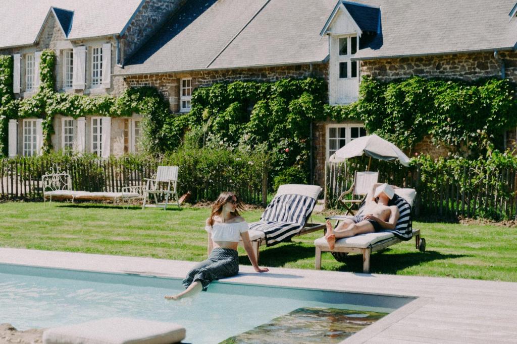a woman sitting in a swimming pool next to a man at Maison Hyacinthe in Saint-Pierre-Langers