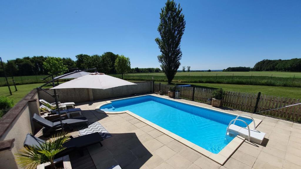 a swimming pool in a yard with an umbrella at Le Clos de La Réserve in Cinq-Mars-la-Pile