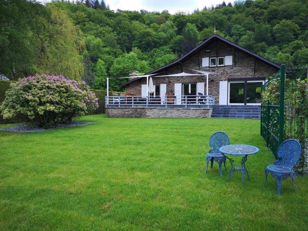 two chairs and a table in a yard with a house at La Semois Et Moi in Rochehaut