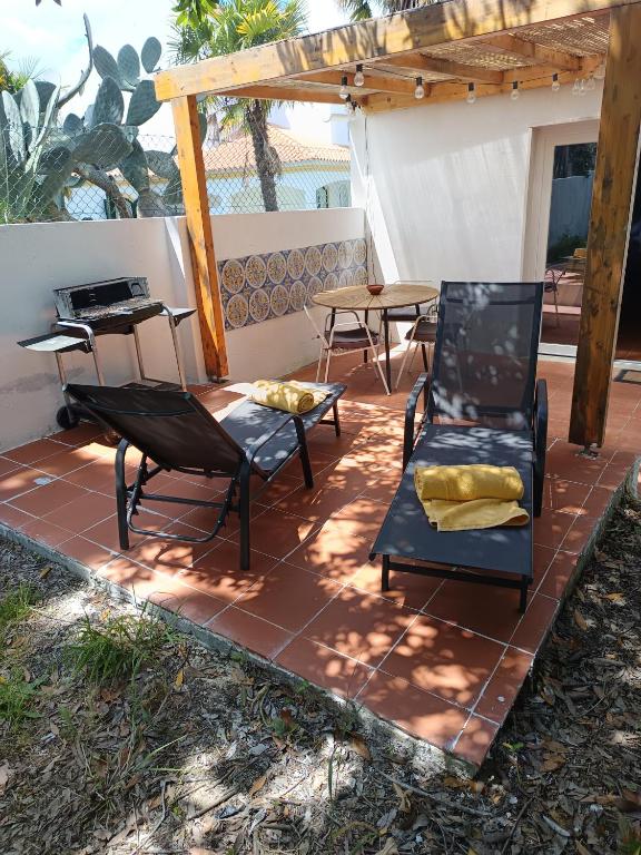 a patio with chairs and a table and a grill at Oficina do Avô in Villa Nogueira
