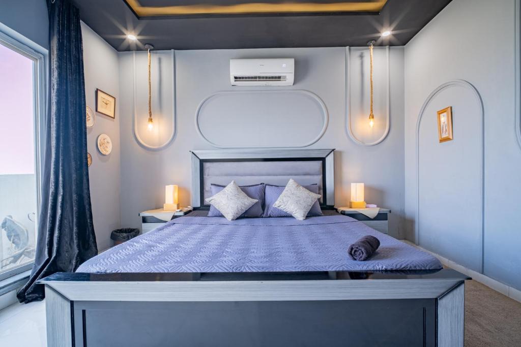 a bedroom with a bed with blue sheets and two lamps at Modern executive stay in Lahore Long stay ready in Lahore