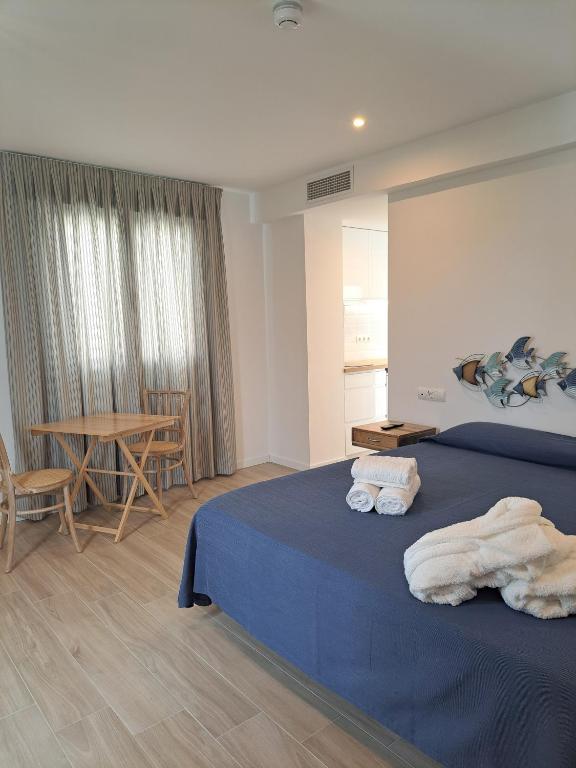 a bedroom with a bed and a table with chairs at Aparthotel ALMARIS in Es Pujols