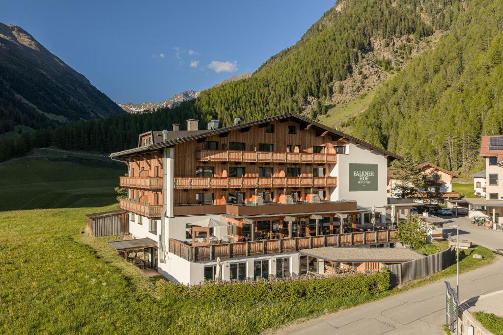 a building on a hill with a mountain at Naturhotel Falknerhof in Niederthai