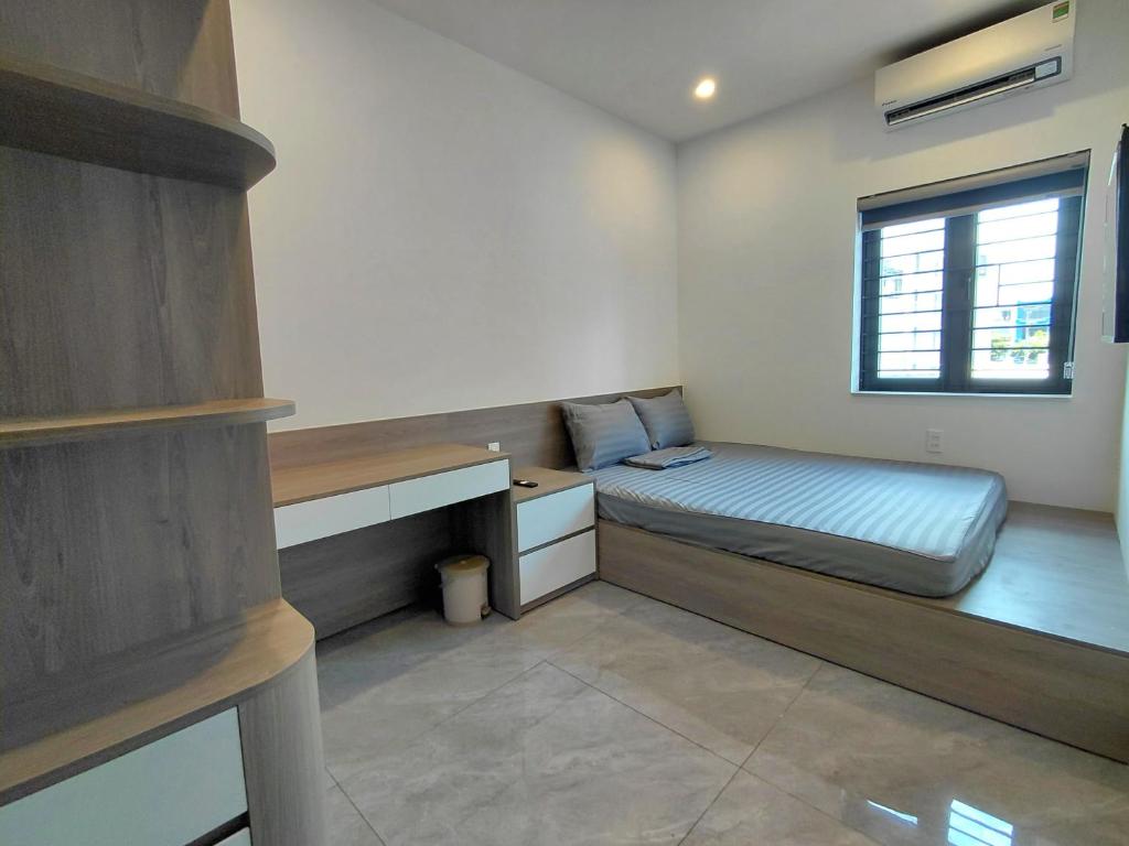 a bedroom with a bed and a desk and a window at ZENITH STAY by Lan's in Danang